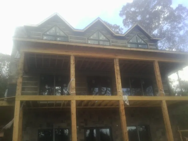 Dormers and porch framing on a large log home under construction — Roof Coating work by our crew in Frost