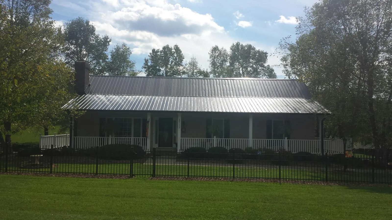 Gray metal roof on a brick ranch with a full width front porch — Gutter Guard Installation work by our crew in Frost