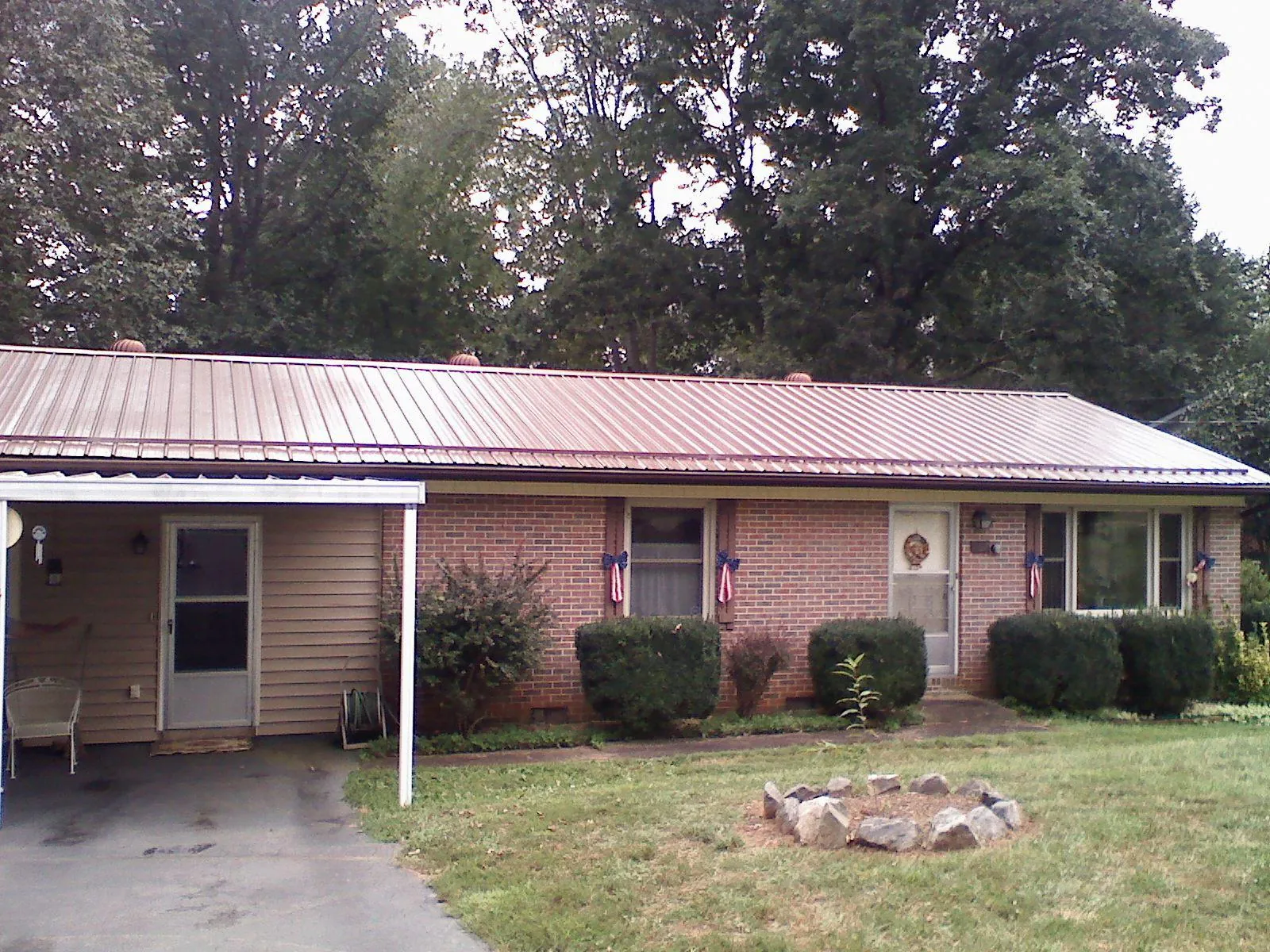 Bronze metal roof and carport on a brick ranch home — Roof Repair work by our crew in Frost