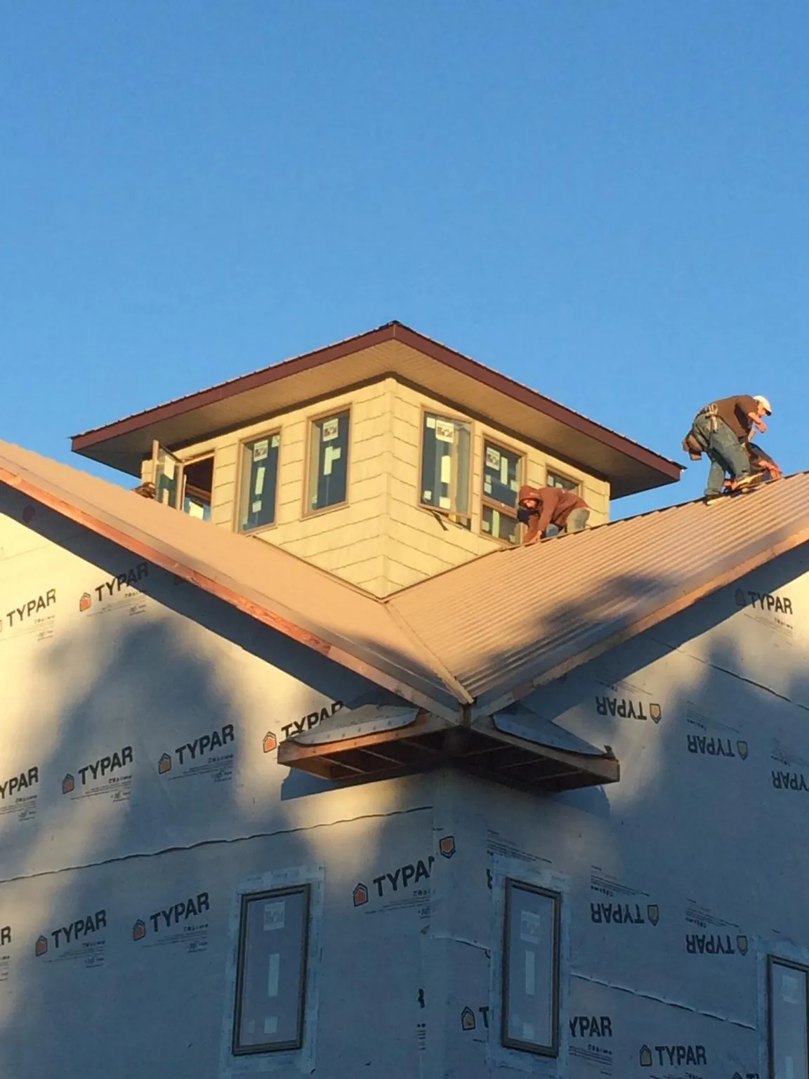 Roofers working around a rooftop cupola on a new metal roof at sunset — Roof Waterproofing in Frost by Roofing Brothers